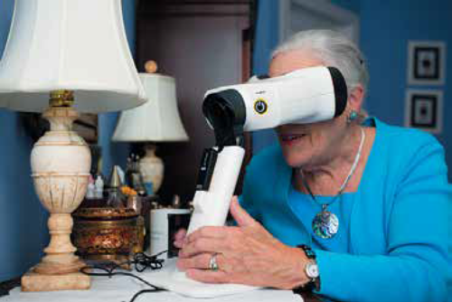 A lady sits at a table and uses an ophthalmological device.